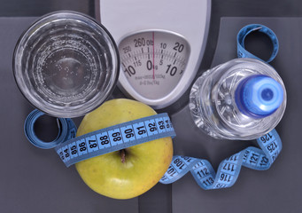 Bottle of water, green apple, glass of water and measuring tape