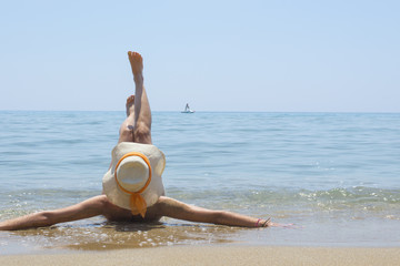 Fototapeta premium Girl lying on the beach with legs lifted up