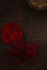 saffron spice in pile threads and powder on old metal background