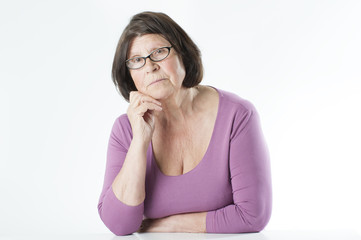 Elderly woman sitting at the table, leaning on her hand..