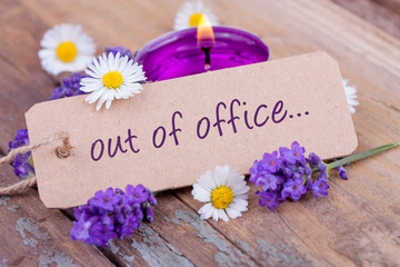 Close-up of candle, lavender flowers and label with text OUT OF OFFICE