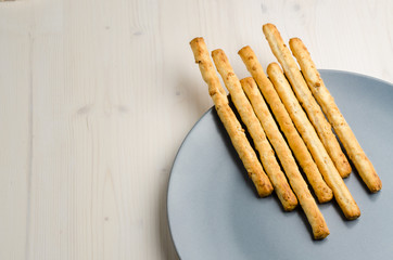 rustic breadsticks in a dish on wood table, close up, background
