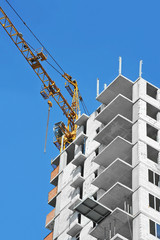 Crane and building construction site against blue sky