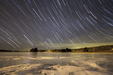 Star trails over lake at night in winter in west virginia