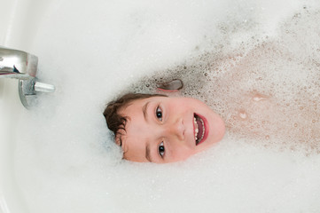 young boy in a bath full of bubbles