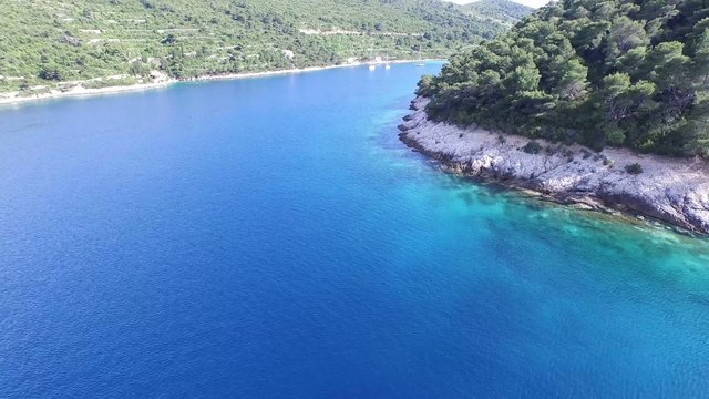 Escena aerea, panorámica, de una bahía de agua transparente, turquesa, en la Costa dálmata. Croacia. Se aprecia el movimiento y brillo del agua.