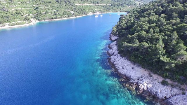 Toma aérea, panoramica. Escena que se traslada a través de la costa rocosa. Situado en la costa Dálmata, Croacia. Isla idílica con barcos de vela anclados en el extremo de la bahía.