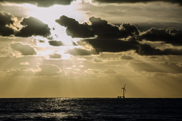 Windrad im Meer am Horizont mit Sonnenuntergang