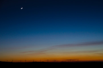 Windräder auf Gebirgskamm in der Nacht mit Mond