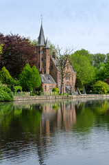 Naklejka premium Flemish style castle reflecting in Minnewater lake in Bruges