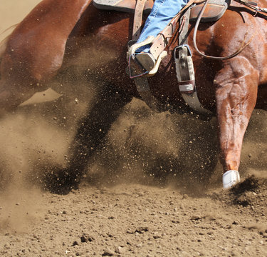 A  close up action photo of a horse sliding around a barrel with dirt flying.