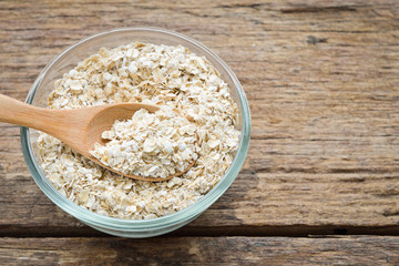 Cup of rolled oat flakes oatmeal on old wooden table