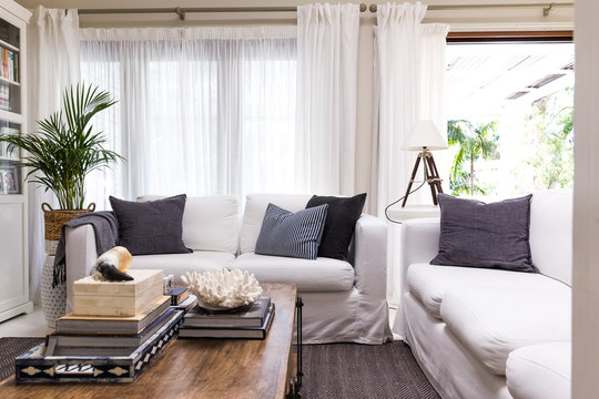 White linen sofas and a coffee table in a stylish tropical style living room with open doors