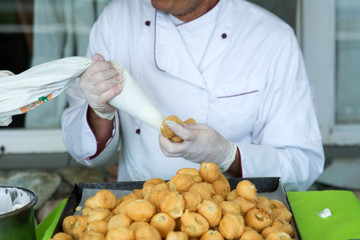 Pasticcere all'opera: riempire i bignè al fine di assemblare una torta.