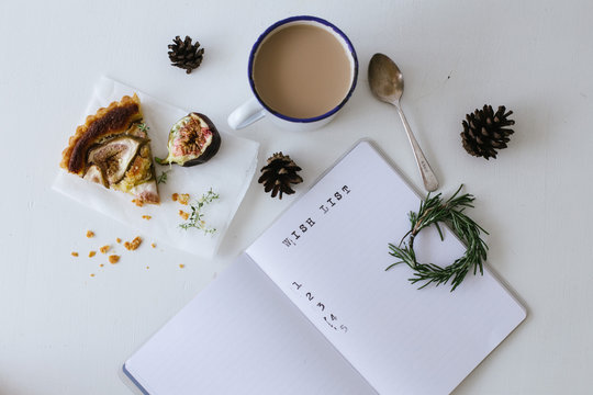 Overhead view of a Blank Wish list with a mug of tea and slice of fig and almond tart on a table