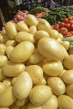 fresh potatoes and vegetables on a market stall 