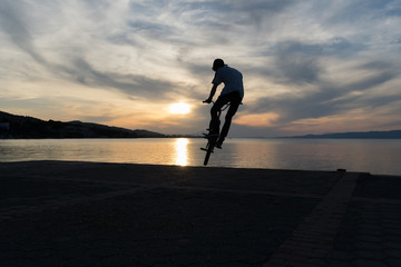 Silhouette of a bmx biker against the sun.
