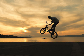 Fototapeta na wymiar Stunning tricks of bmx biker against the sunset. 