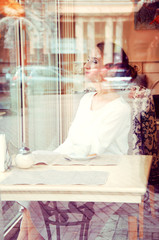 Beautiful elegant blonde sitting in a cafe drinking tea.View thr