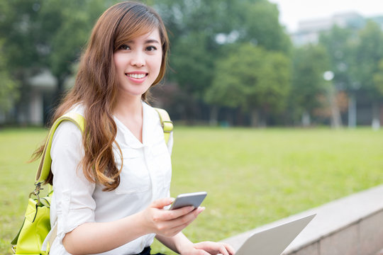 Asian beautiful female studen using mobile phone in campus