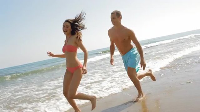 young couple running and chasing on the beach