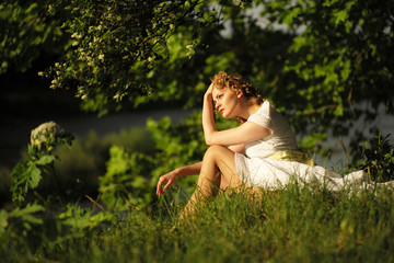 Naklejka na ściany i meble Woman in dress sitting on grass