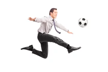 Fotobehang Young businessman kicking a football and smiling © Ljupco Smokovski