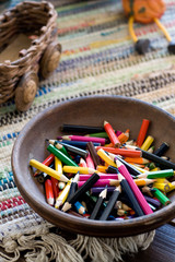 Many colored pencils lying in a clay plate