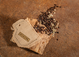 Tazza in tela di juta con chicchi di caffè crudo e tostato su legno grezzo e  texture di ruggine.