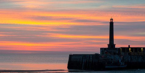 Sunset at Margate, Kent, England, showing part of he harbour wall and the lighthouse