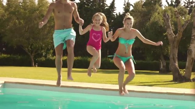 Slow motion of family jumping in pool.