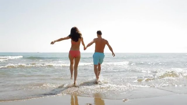 young couple running and playing in surf
