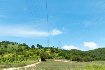 a power mast of a high voltage transmission line against blue sky with sun