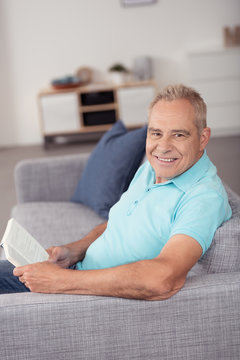 entspannter senior liest ein buch auf dem sofa