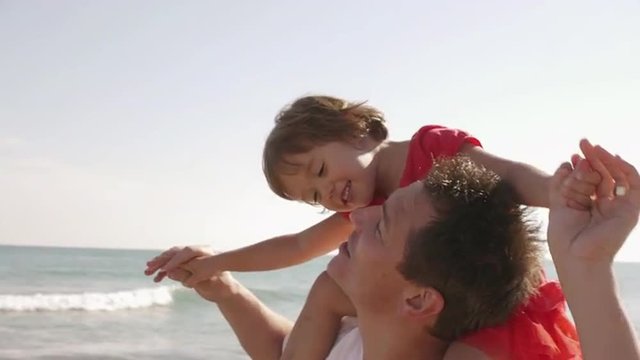 Father giving his daughter a shoulder ride at beach.
