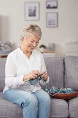 moderne seniorin strickt auf dem sofa