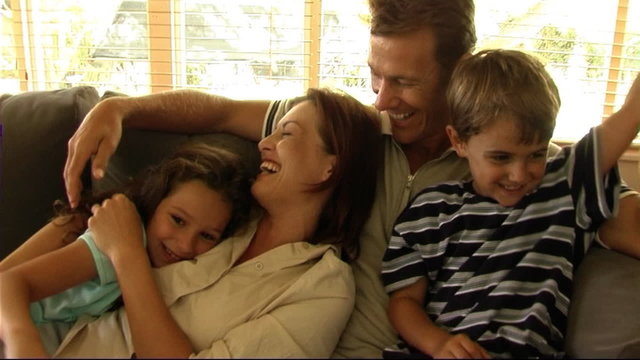 Family on sofa cuddling and tickling