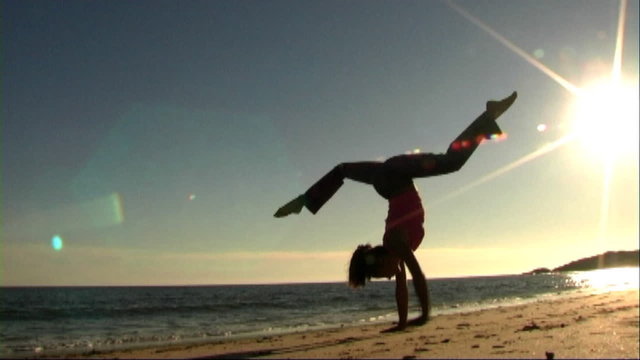 Woman on beach doing acrobatics
