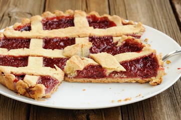 Old fashioned lattice flan with strawberry jam cut with metal sp