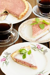 Strawberry tart with two cut pieces decorated with fresh mint an