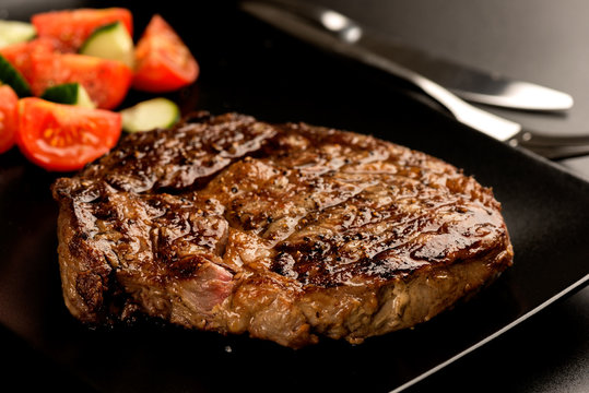 Grilled steak and vegetables on dark plate