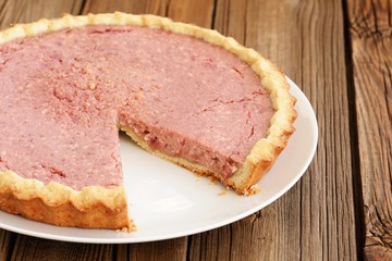 Strawberry tart with cut one piece missing on old wooden table