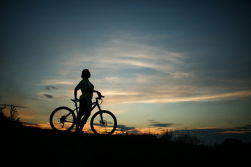 Silhouette of tourist and bike on sky background.