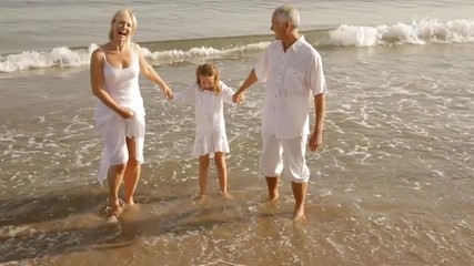 grandparents and granddaughter standing on beach