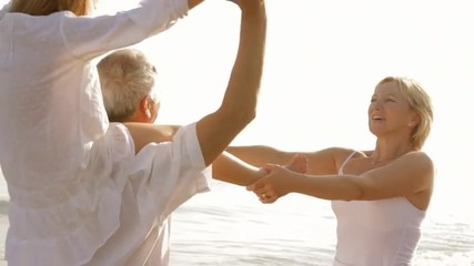 grandparents and granddaughter playing on beach