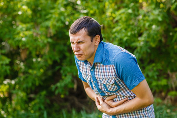 Man on the street abdominal pain on a green background leaves su