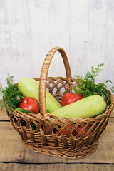 fresh vegetables, cucumbers, squash, tomatoes and fennel in a wicker basket on wooden background