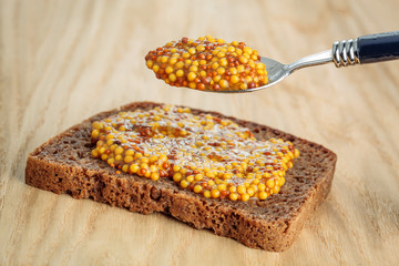 Rye bread slice witth spoon of wholegrain mustard