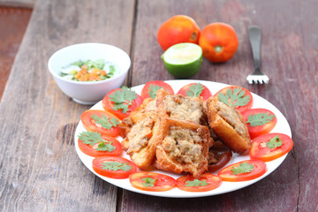Fried bread with minced pork spread on wood table.