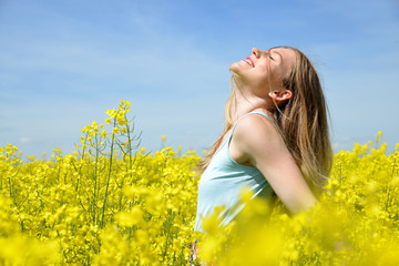 Naklejka na ściany i meble Young happy woman on blooming rapeseed field in spring